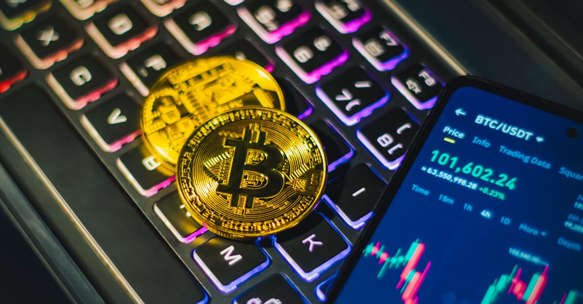 Bitcoin coin resting on a backlit keyboard with a cryptocurrency trading app on a smartphone